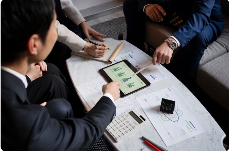 Multiple people at a meeting, pointing at a tablet